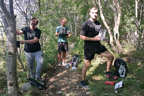 3 young men Installing footfall sensors in a forest