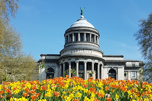 Royal Museum of Art and History in Brussels - a majestic building, surrounded by yellow and orange spring flowers.
